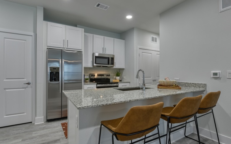 A kitchen with stainless steel appliances and white cabinets at Alta Westover Hills luxury apartments in San Antonio, TX.