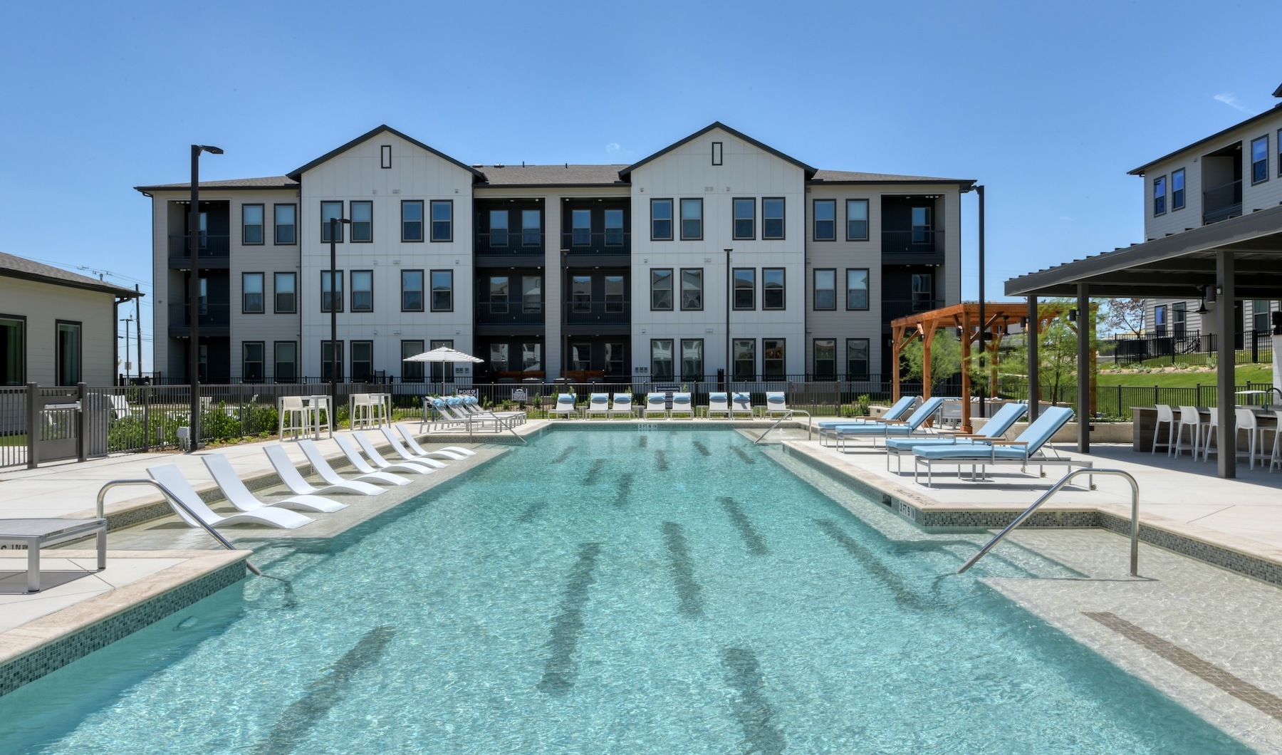 Poolside view of sun shelf and Alta Westover Hills apartments for rent in San Antonio, Texas.